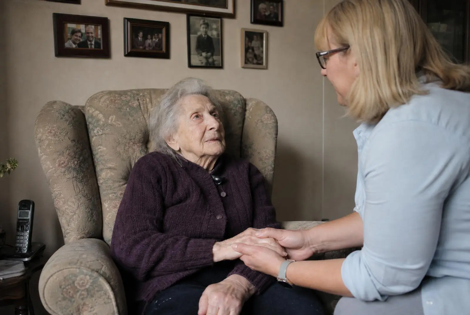A caregiver gently looking through a family photo album with an older woman at home